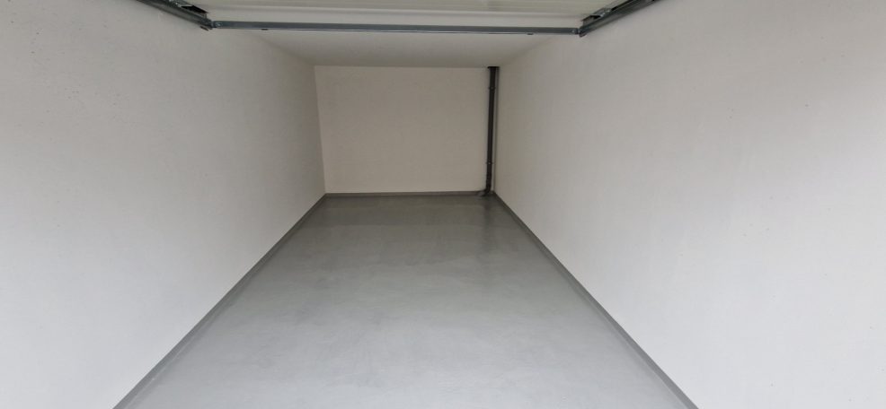 Leerer Raum mit weißen Wänden und einem grauen Boden.